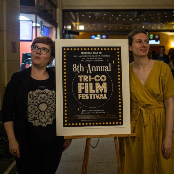 Tri-Co Film Festival Co-directors Dajana Denes Walters and Sophia Abraham-Raveson '18 stand in front of the entrance to Bryn Mawr Film Institute with a poster of the festival.