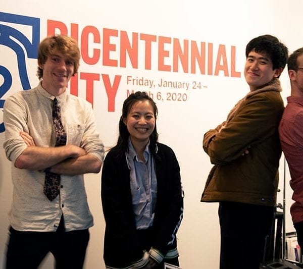 Four of the student filmmakers stand in front of the wall with the exhibit's name on it