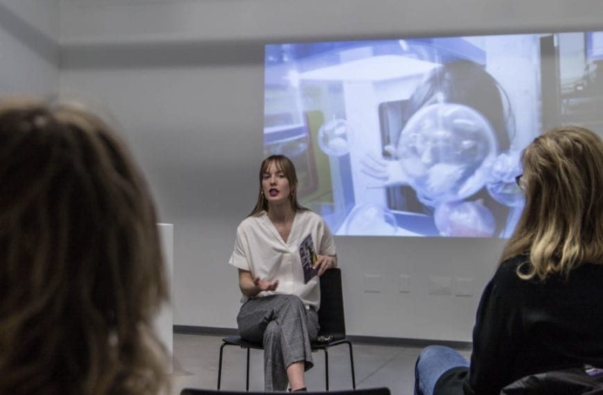 Curator Courtney Lynne Carter sits in front of a crowd talking about the videos on display