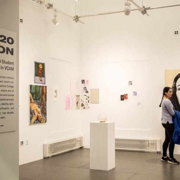 A glimpse into the gallery with artwork on the wall and on a pedestal