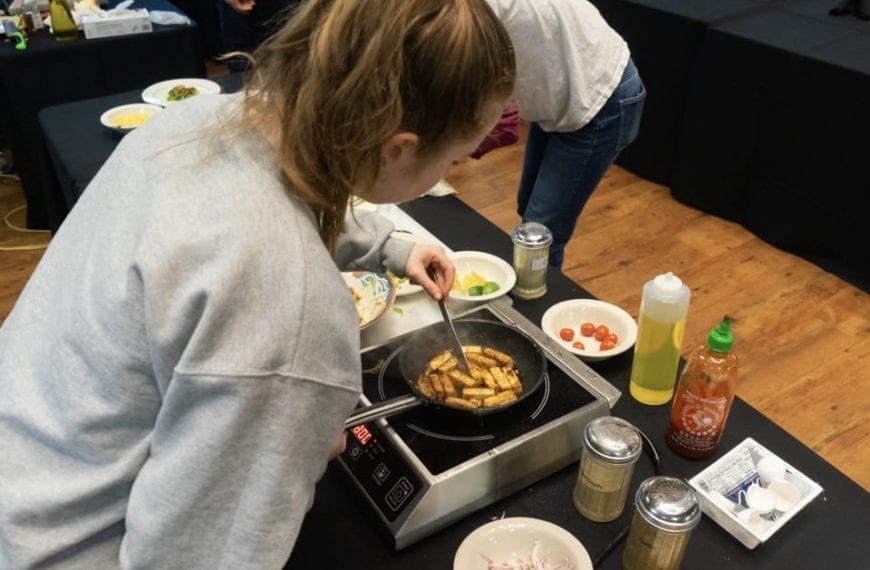 Photographed from behind, a student stirfries some spicy tofu