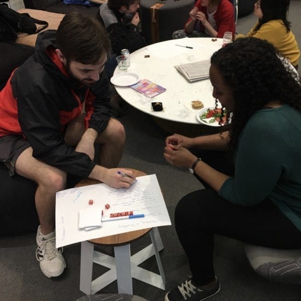 Two students plot out their games with a bunch of die