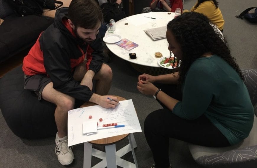 Two students plot out their games with a bunch of die