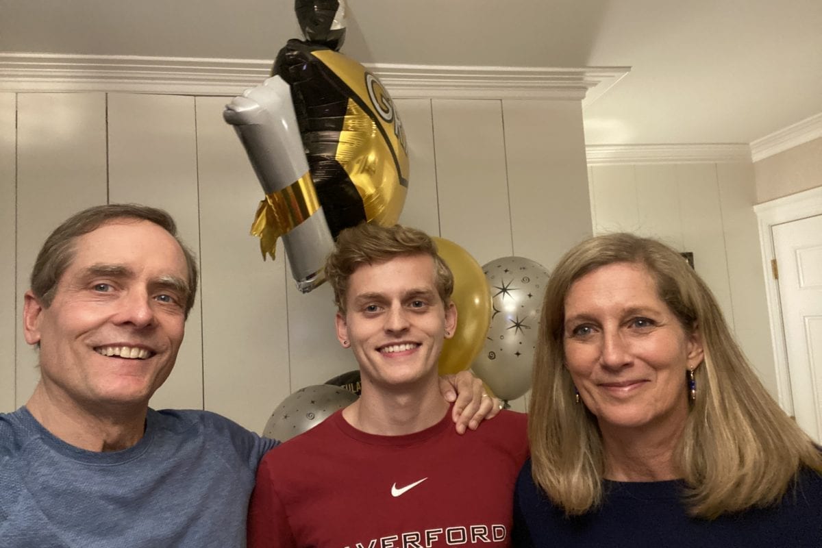 James Barker between his parents wearing a Haverford t-shirt and holding graduation balloons