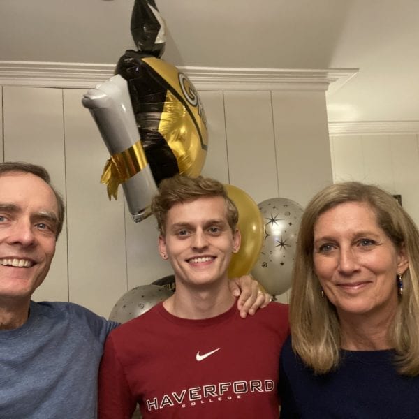 James Barker between his parents wearing a Haverford t-shirt and holding graduation balloons