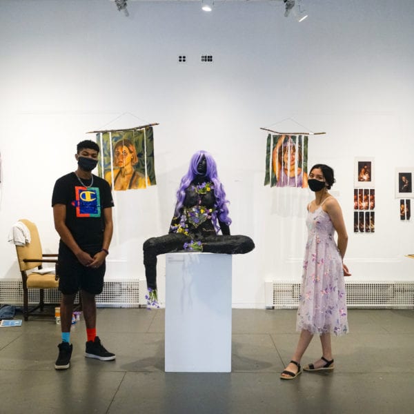 Jalen Martin '23 and Izzy Ray '23 stand in the student art center amidst the art pieces of In the Works, the exhibit they curated together.