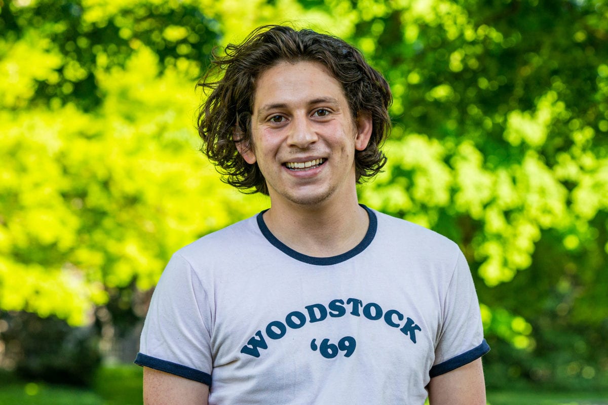 Headshot of Federico wearing white shirt with "Woodstock '69" in blue writing on it.