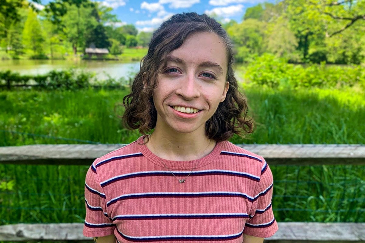 Headshot of Grace wearing a striped pink shirt in front of the duck pond.