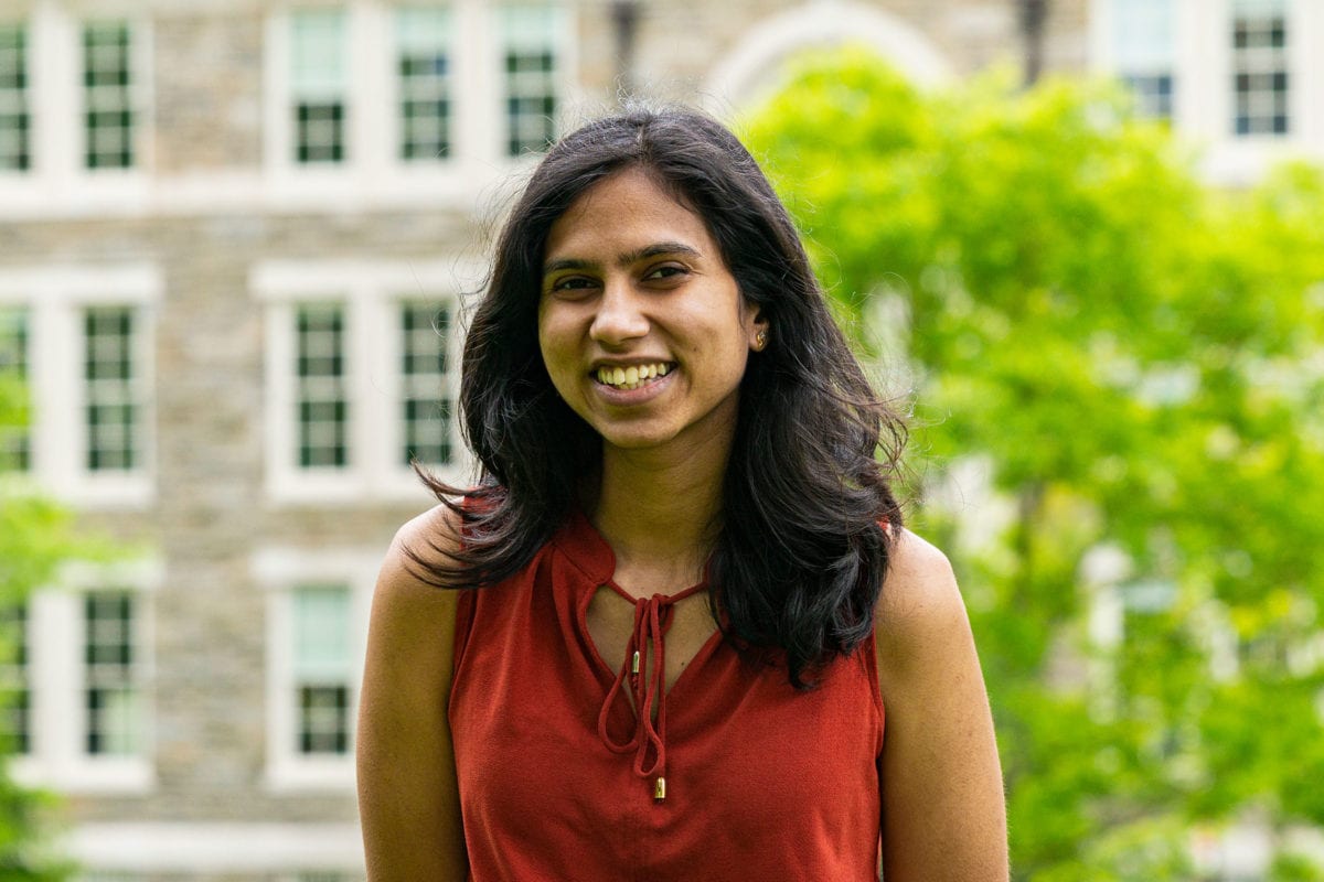 Headshot of Shreya in a red shirt standing in front of the KINSC.