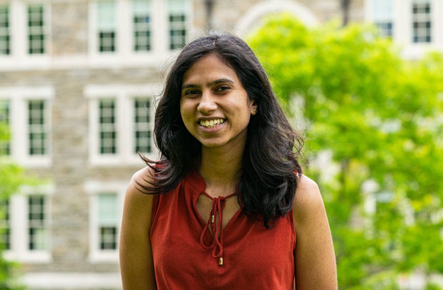 Headshot of Shreya in a red shirt standing in front of the KINSC.