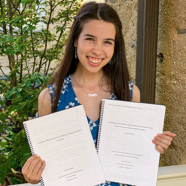 Photo of Benjamin holding her two theses in Founders courtyard.