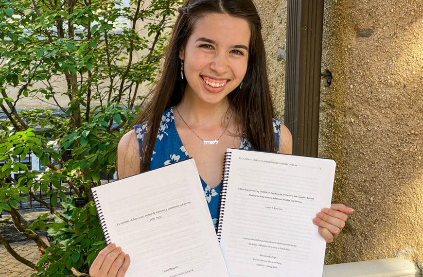 Photo of Benjamin holding her two theses in Founders courtyard.