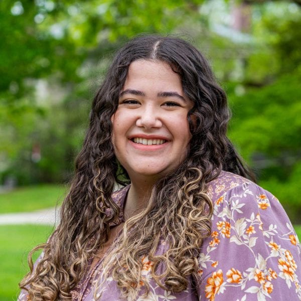 Headshot of Claudia smiling on Founders Green in a floral shirt