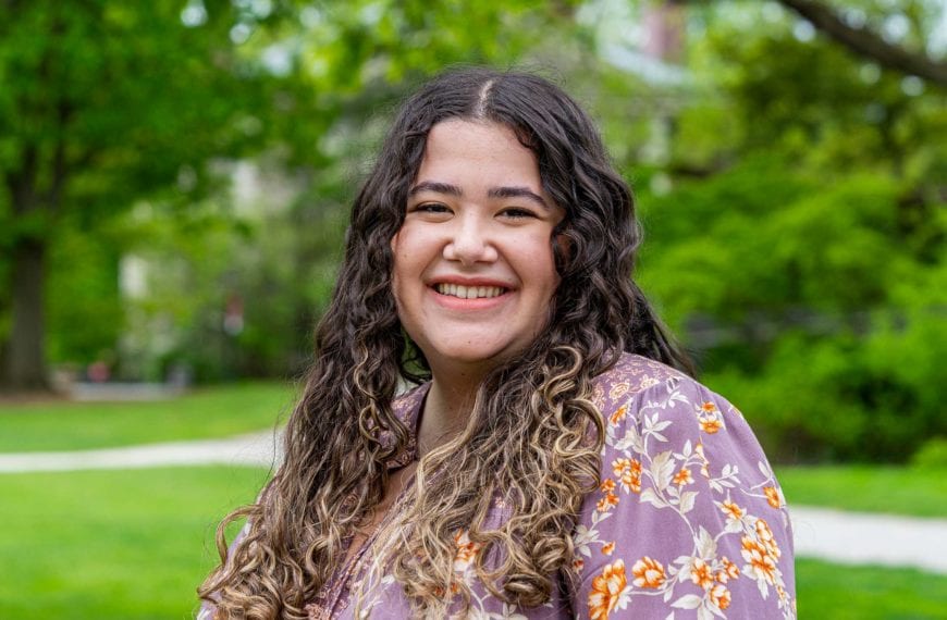 Headshot of Claudia smiling on Founders Green in a floral shirt