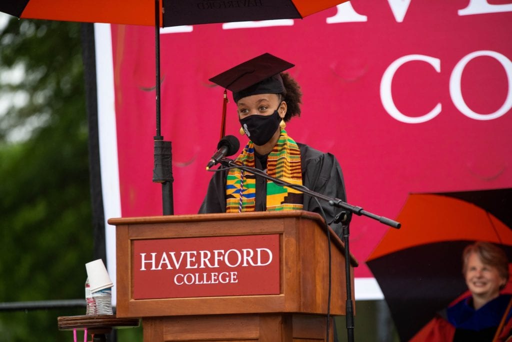 Lourdes Taylor wearing a squirrel mask and black cap and gown gives her graduation speech from the Haverford podium.