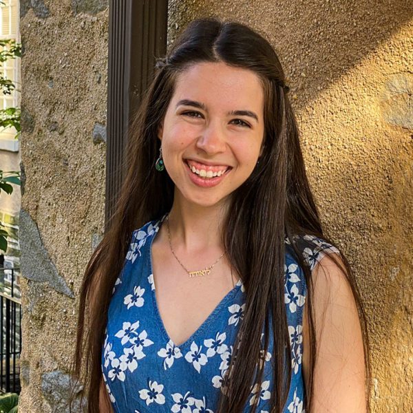 Laurel Benjamin smiles wearing a blue and white dress in Founders Courtyard