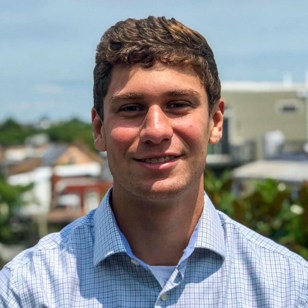 A picture of Brett wearing a blue button down with a city in the background.