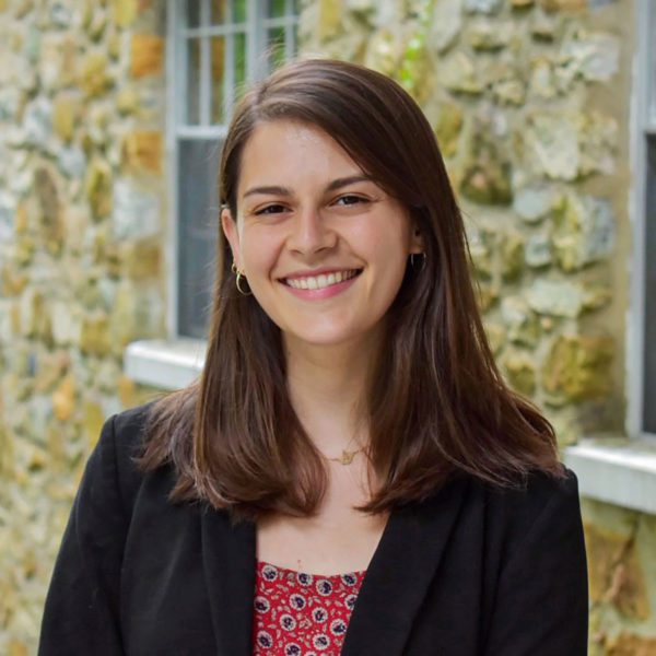 A headshot of Eliza in front of a stone building.