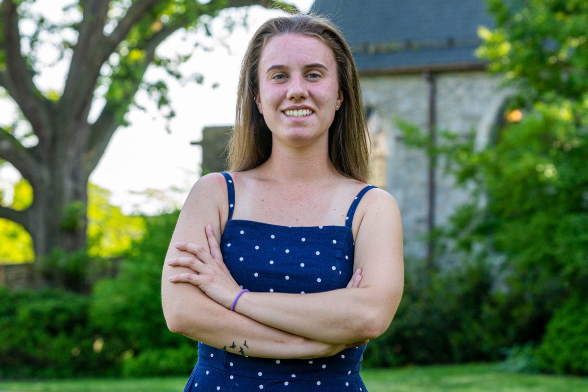 A picture of Molly in a blue dress with white polka dots, standing in front of the library.