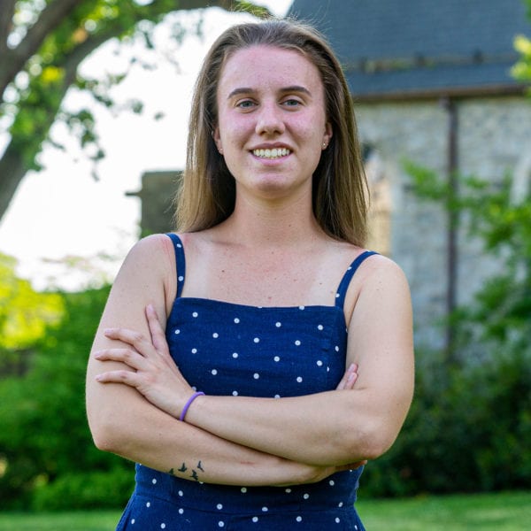A picture of Molly in a blue dress with white polka dots, standing in front of the library.