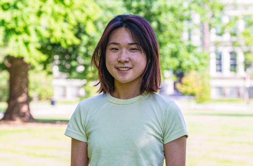 Headshot of Shufan in a yellow-green shirt standing in front of the KINSC.