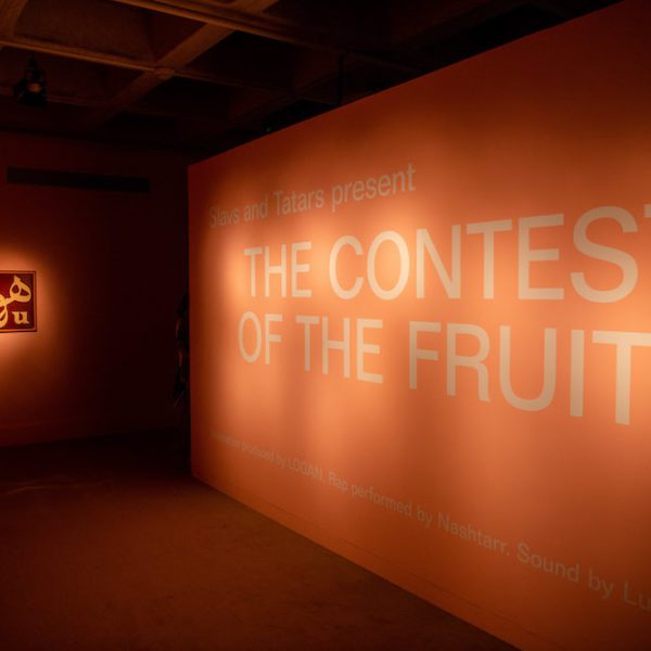 A spotlight on a salmon-colored wall with a sign reading "The Contest of the Fruits"
