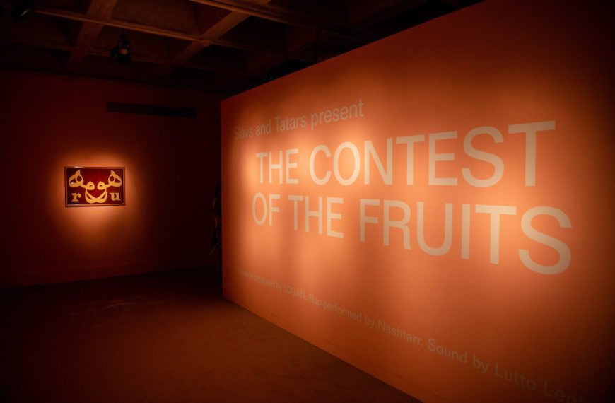 A spotlight on a salmon-colored wall with a sign reading "The Contest of the Fruits"