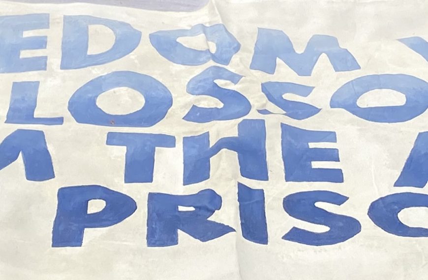 A protest sign that reads "Freedom Will Blossom From The Ashes Of Prisons"