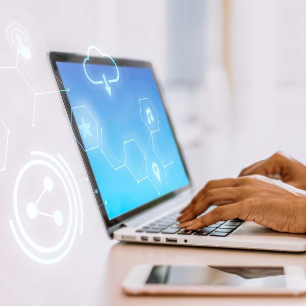 An image of a pair of hands typing at a laptop and a web of symbols projected from it.
