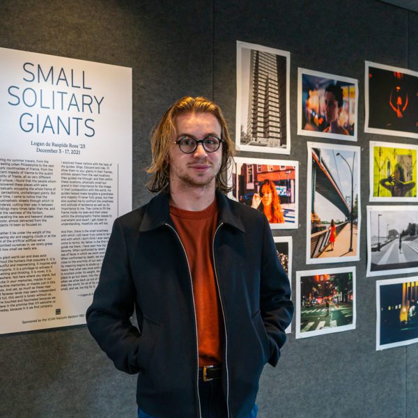 Logan de Raspide Ross '23 standing in front of the poster board at his new exhibition.