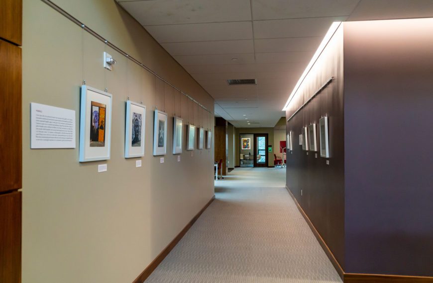The Art of Politics informational board is on the wall of Lutnick Library next to four photographs taken by curator Jack Weinstein '23