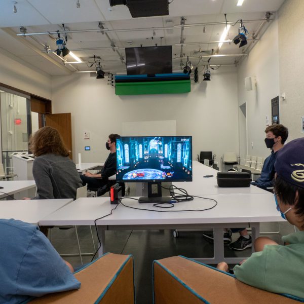 Two students play a game of Super Smash Bros. Ultimate on a monitor.