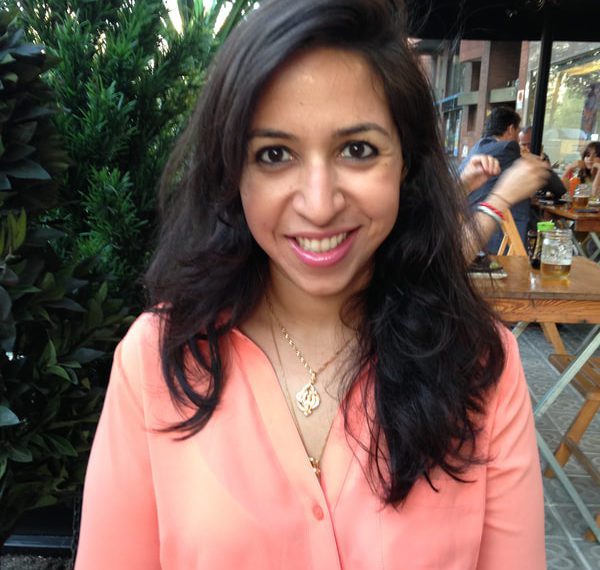 Niloufer smiles sitting at an outdoor cafe