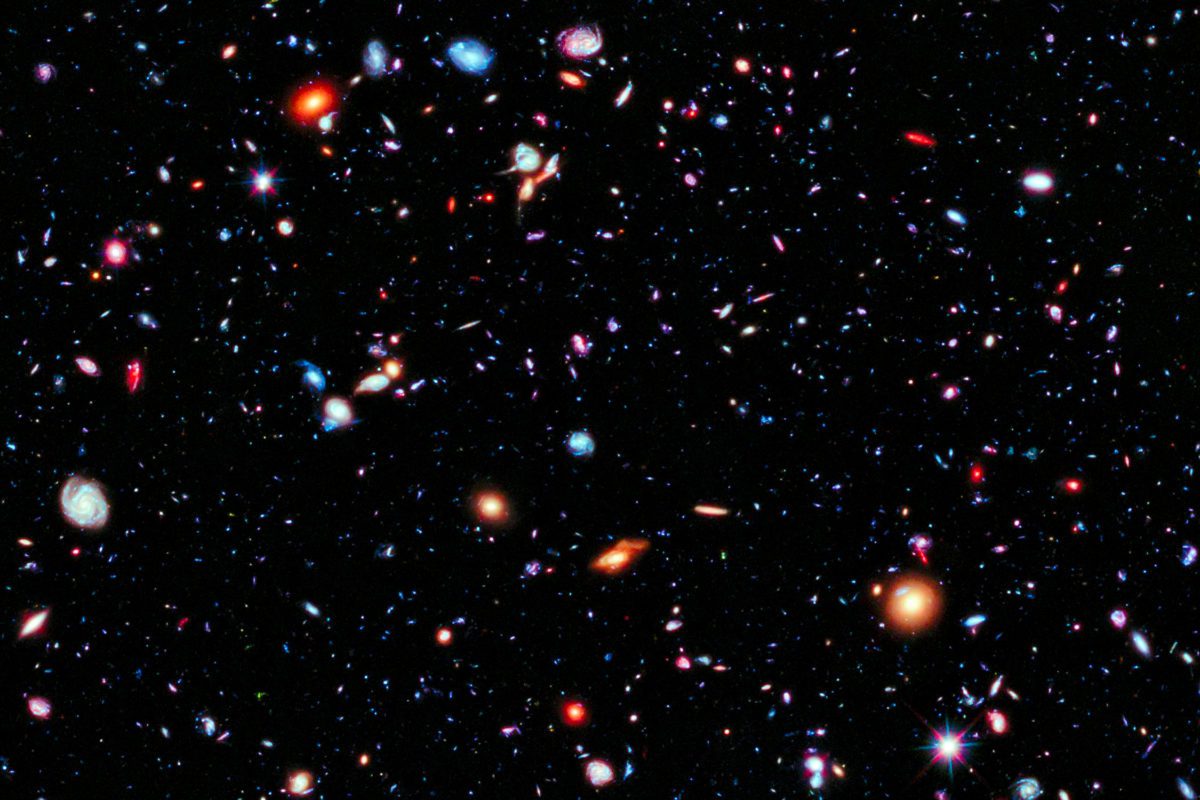 Dots and smears of orange and blue light against the blackness of space represents the farthest view of our universe.