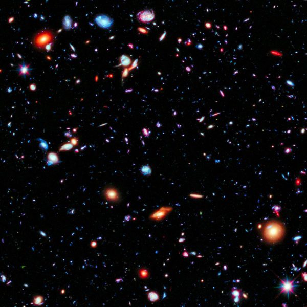 Dots and smears of orange and blue light against the blackness of space represents the farthest view of our universe.