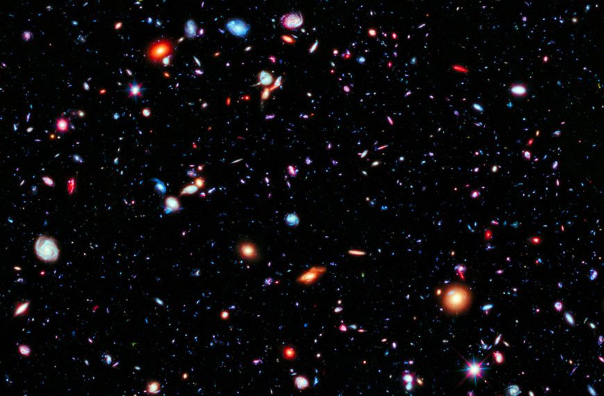 Dots and smears of orange and blue light against the blackness of space represents the farthest view of our universe.
