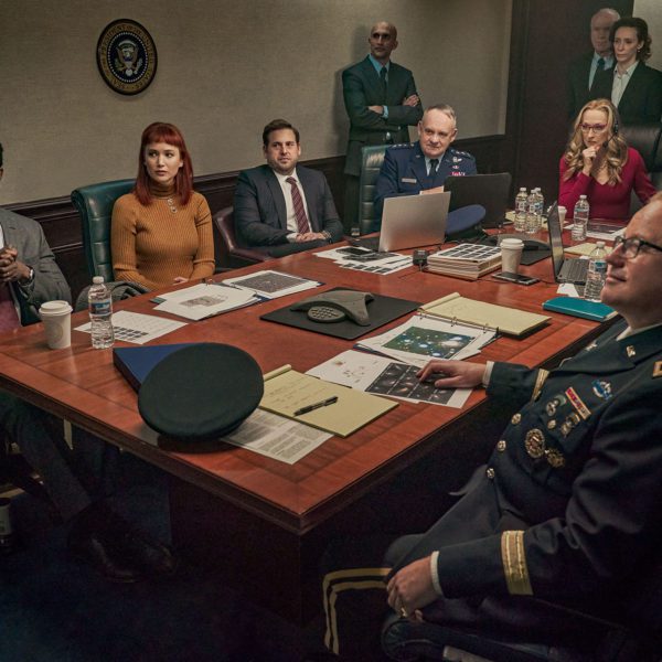 Jennifer Lawrence, Leonardo DiCaprio, Meryl Streep, Jonah Hill, and several other actors dressed in high-ranking military costume sit around a table in the Situation Room in a scene from Don't Look Up.