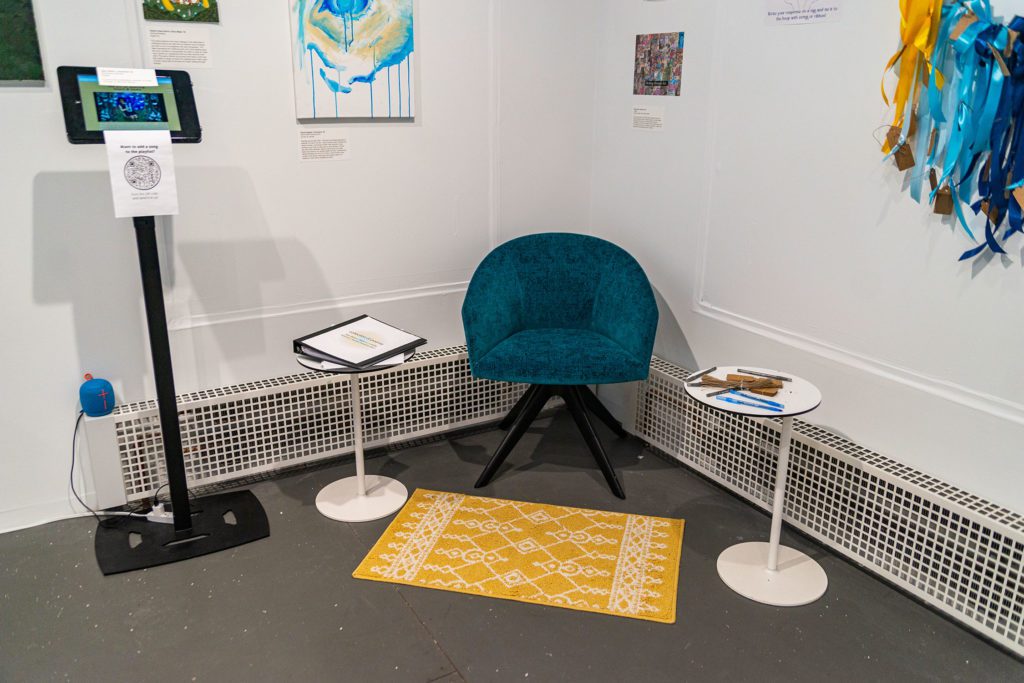 A blue chair with a yellow mat in front of it surrounded by different art