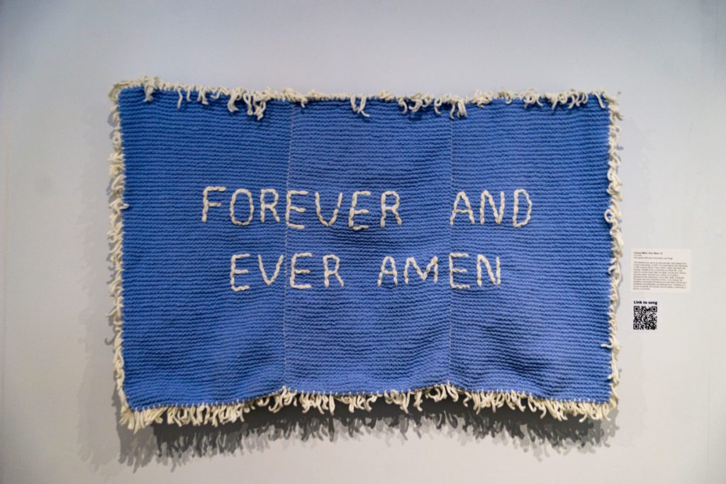 A blue tapestry with the words "Forever and Ever Amen" stitched into it