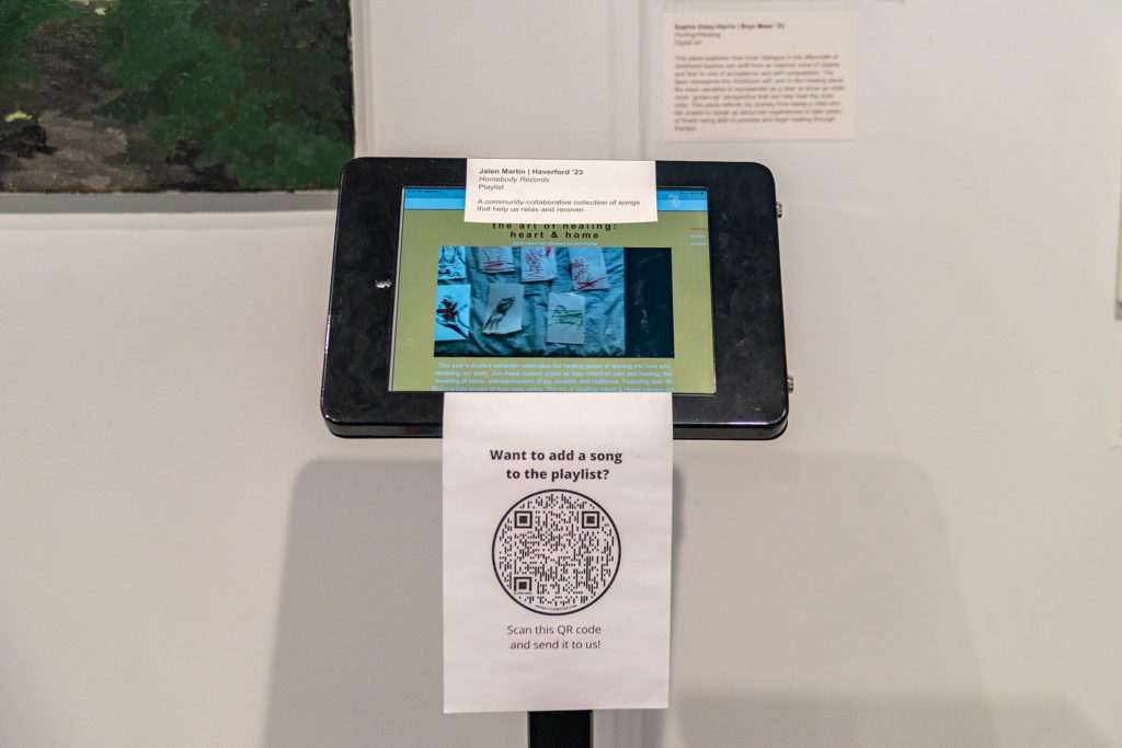 A tablet with a piece of paper with a QR code taped to it so people can listen and contribute to a collaborative playlist