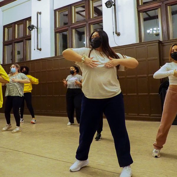 Seven dancers practicing a move during choreography.