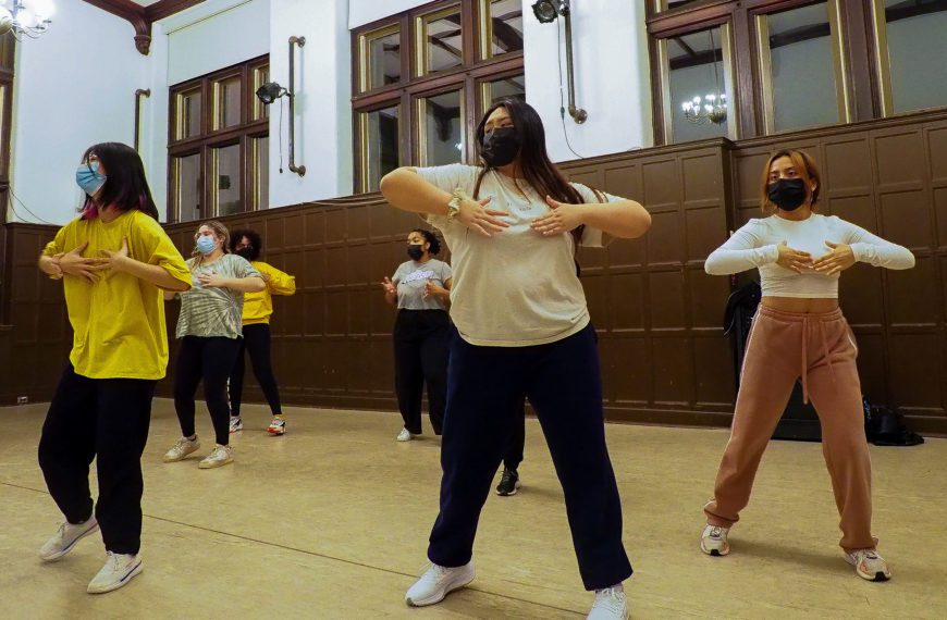 Seven dancers practicing a move during choreography.