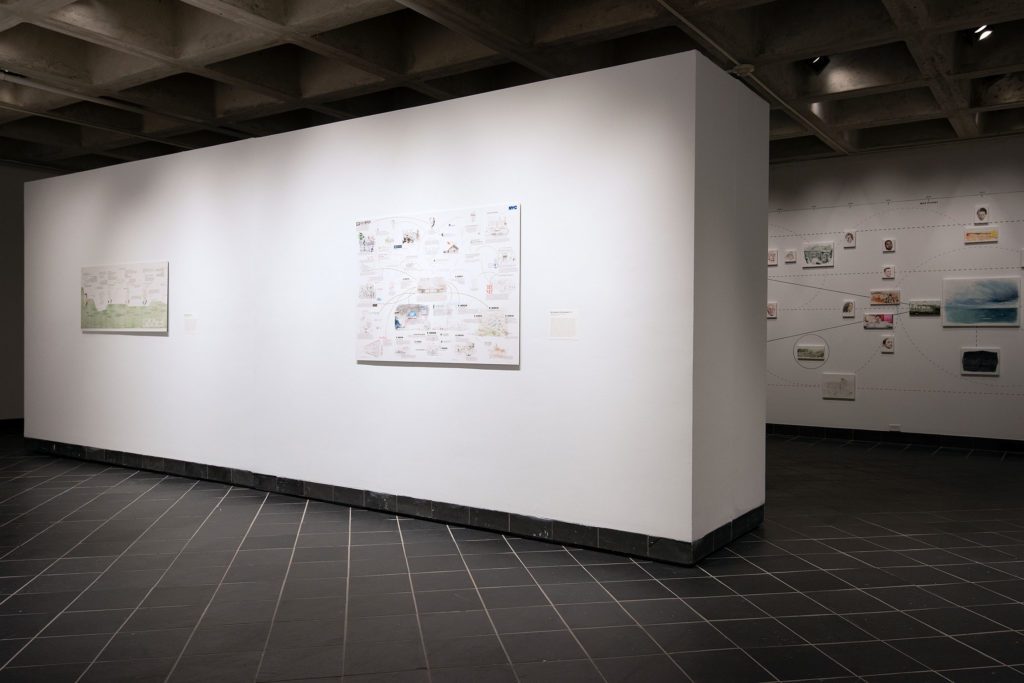 A view of several drawings from "Possibilities of Representation" in the background and the watercolor and collage "Koch Industries (Private Company)" in the foreground