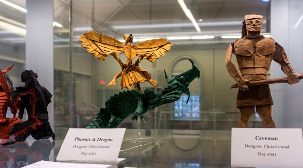 A yellow phoenix, a green dragon, and a brown caveman are among the items in the display case.