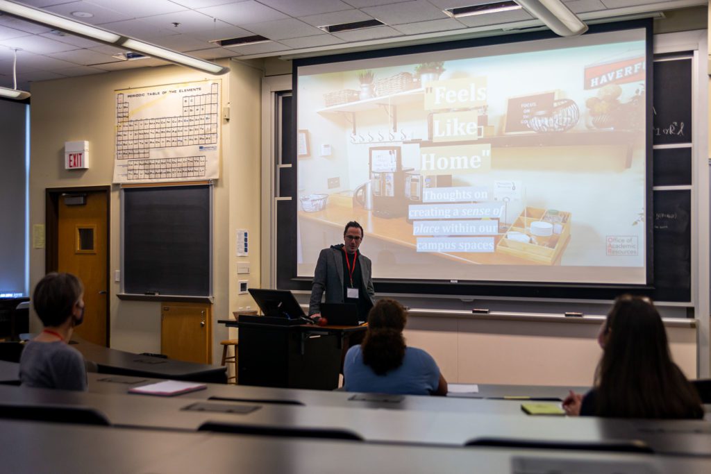 Brian Cuzzolina stands at the front of an auditorium and introduces his presentation, “Feels Like Home: Thoughts on Creating a Sense of Place Within Our Campus Spaces."