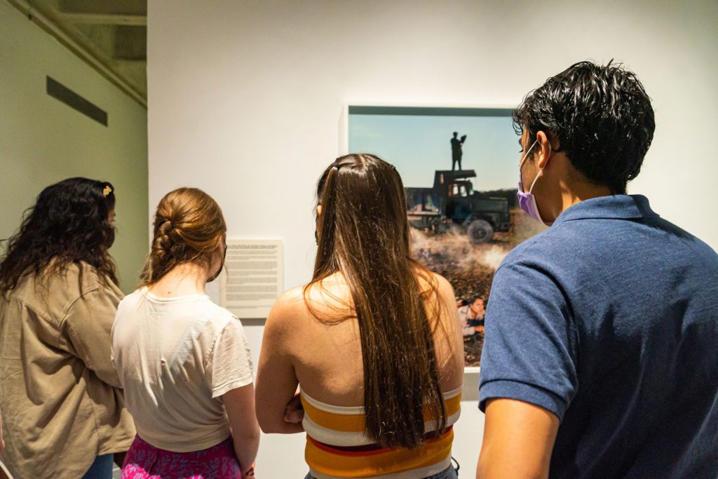 Four students gather around a photo of a soldier standing on a truck