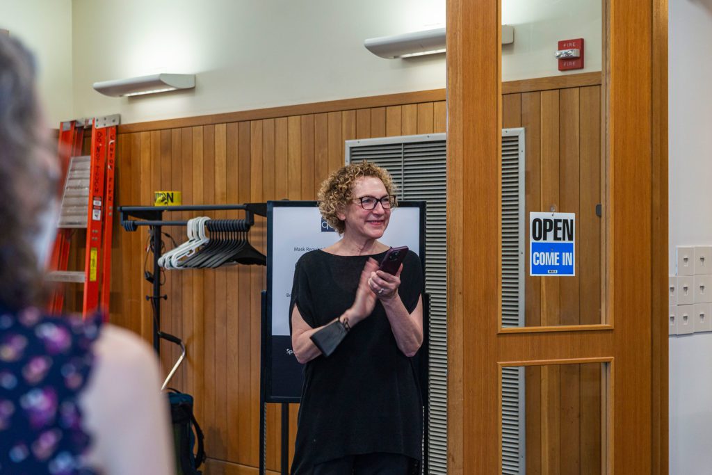 Sally Berger claps while standing at the doorway to the gallery.