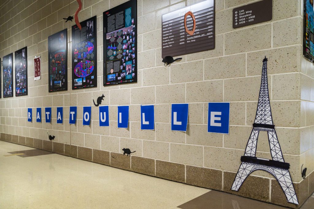 Letters spelling "Ratatouille" are taped to the wall along with many cutouts of rats and a depiction of the Eiffel Tower