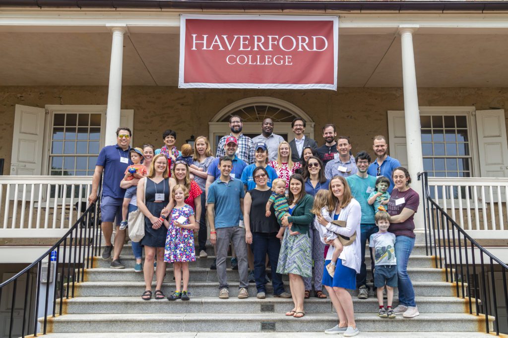 About 30 people from the Class fo 2007 pose for a portrait, severla with their young children and a few holding babies.