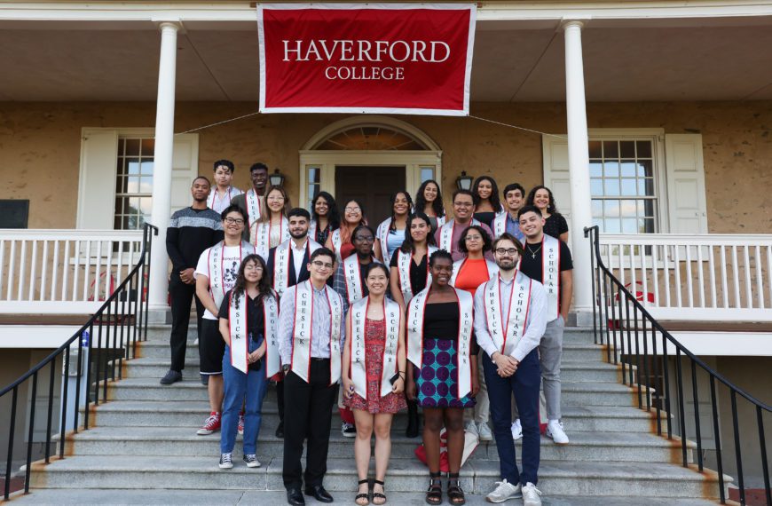Chesick Scholars stand on the porch of Founders Hall under a poster saying Haverford College